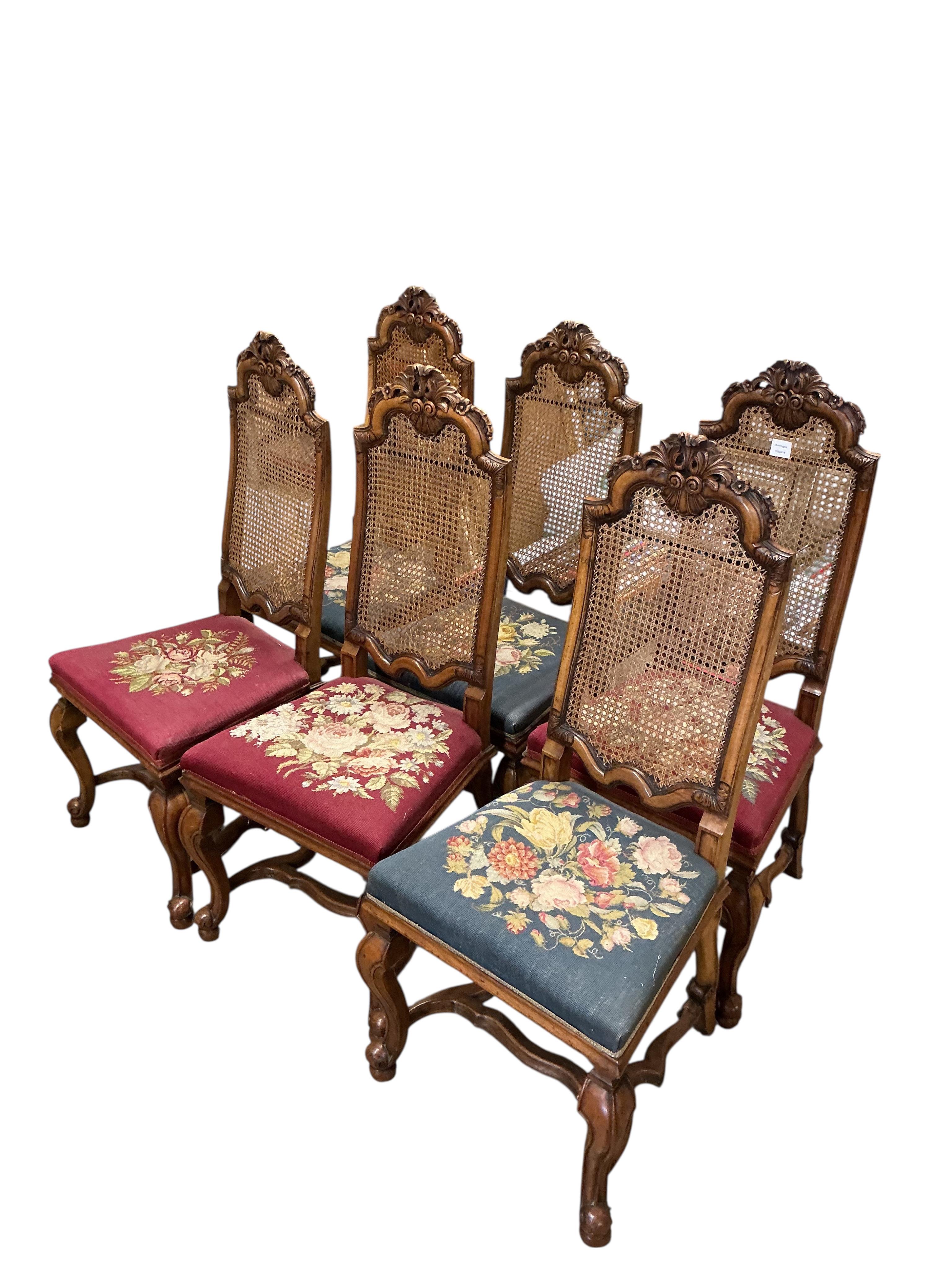 A set of six Carolean style walnut dining chairs with caned backs and floral tapestry seats